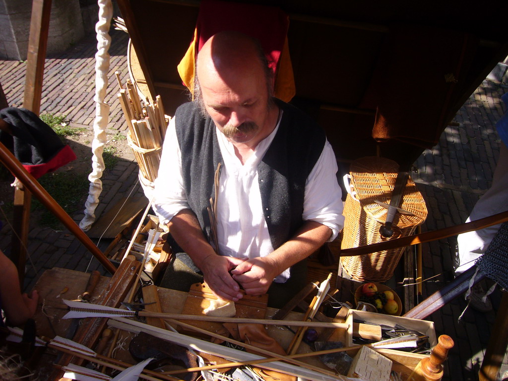 Person in medieval clothes making arrows at the Sint Stevenskerkhof square, during the Gebroeders van Limburg Festival