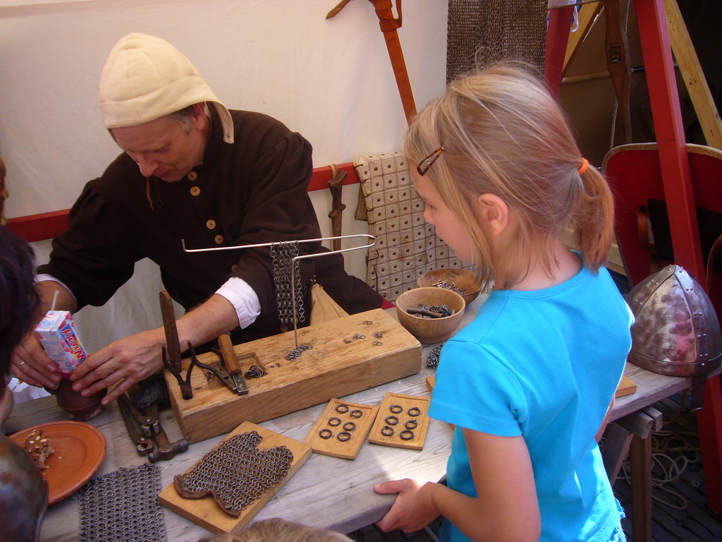 Person in medieval clothes making armour at the Sint Stevenskerkhof square, during the Gebroeders van Limburg Festival