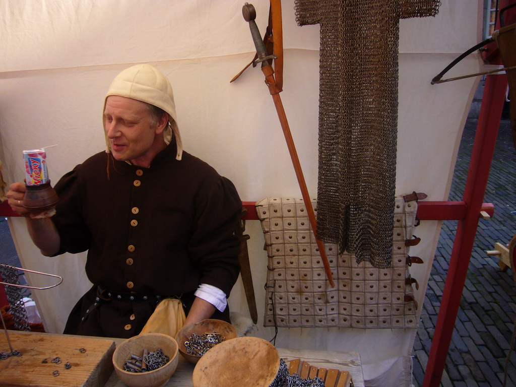 Person in medieval clothes making armour at the Sint Stevenskerkhof square, during the Gebroeders van Limburg Festival