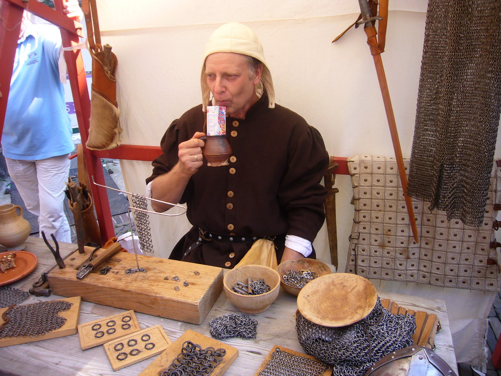 Person in medieval clothes making armour at the Sint Stevenskerkhof square, during the Gebroeders van Limburg Festival