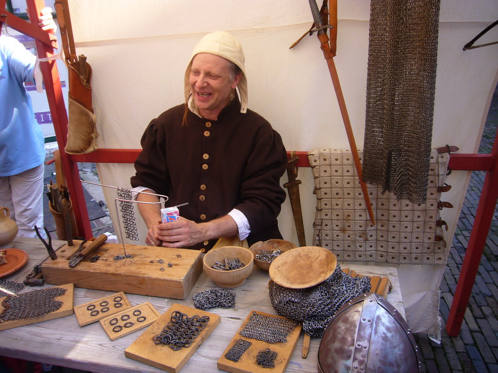 Person in medieval clothes making armour at the Sint Stevenskerkhof square, during the Gebroeders van Limburg Festival