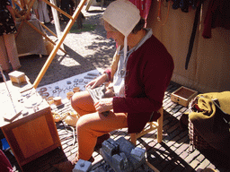 Person in medieval clothes making jewellery at the Sint Stevenskerkhof square, during the Gebroeders van Limburg Festival