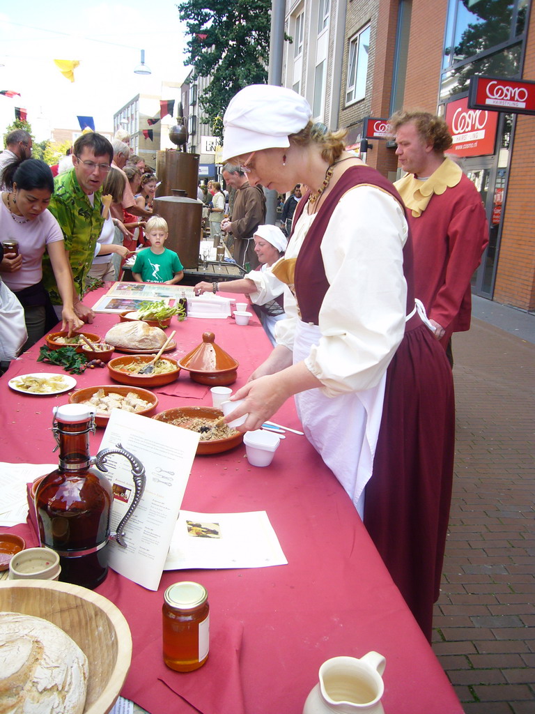 People in medieval clothes selling bread at the Broerstraat street, during the Gebroeders van Limburg Festival