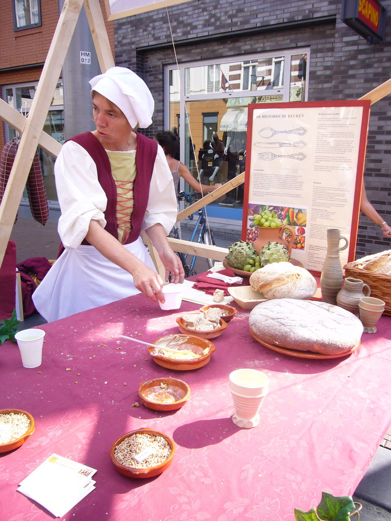 Person in medieval clothes selling bread at the Broerstraat street, during the Gebroeders van Limburg Festival