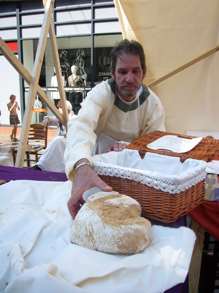 Person in medieval clothes selling bread at the Broerstraat street, during the Gebroeders van Limburg Festival