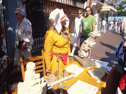 Person in medieval clothes selling wooden statues at the Broerstraat street, during the Gebroeders van Limburg Festival
