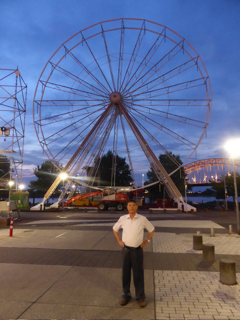 Miaomiao`s father with the ferris wheel at the Waalkade promenade and the Waalbrug bridge over the Waal river, at sunset