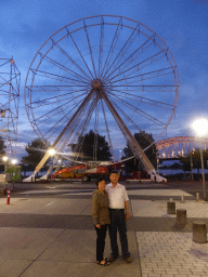 Miaomiao`s parents with the ferris wheel at the Waalkade promenade and the Waalbrug bridge over the Waal river, at sunset