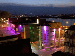 The Waal river with the Nijmegen railway bridge and the Oversteek bridge, the Groene Balkon and Vleeshouwerstraat streets and the `Prinses uit het Oosten` wall painting, viewed from the Valkhof park, by night