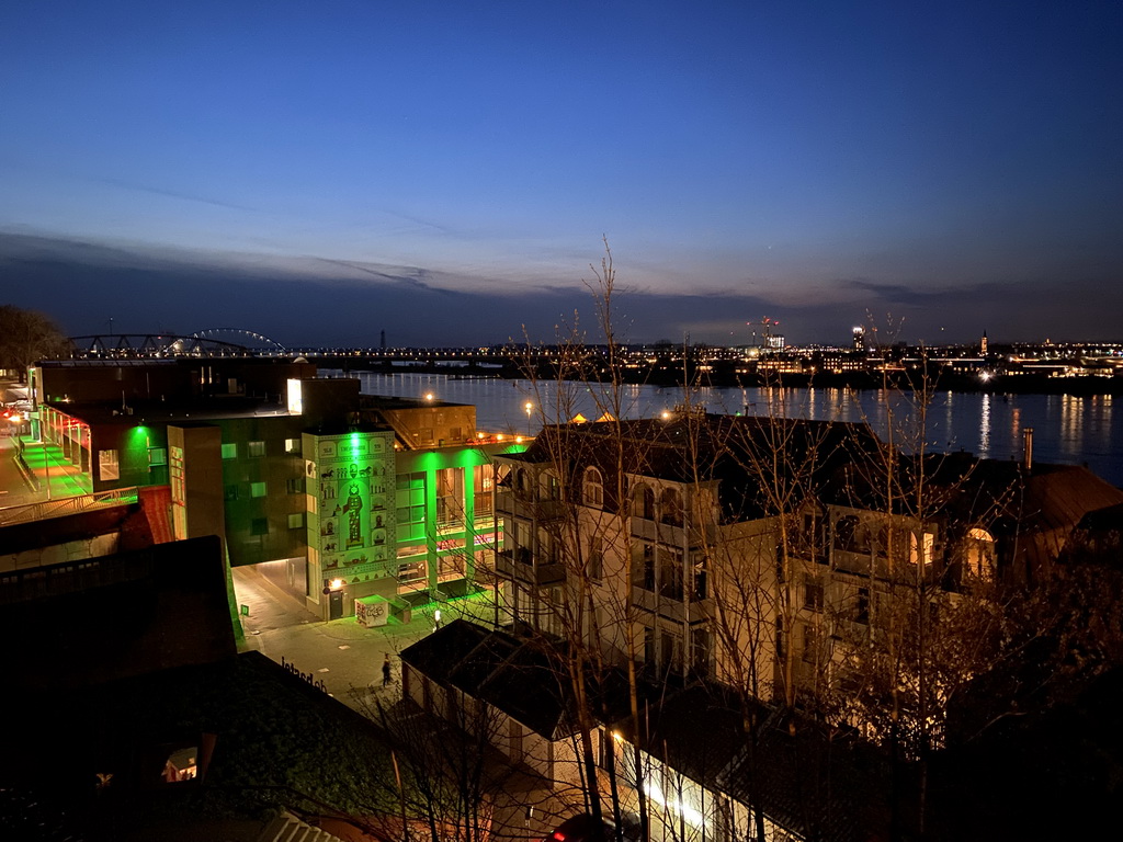 The Waal river with the Nijmegen railway bridge and the Oversteek bridge, the Groene Balkon and Vleeshouwerstraat streets and the `Prinses uit het Oosten` wall painting, viewed from the Valkhof park, by night