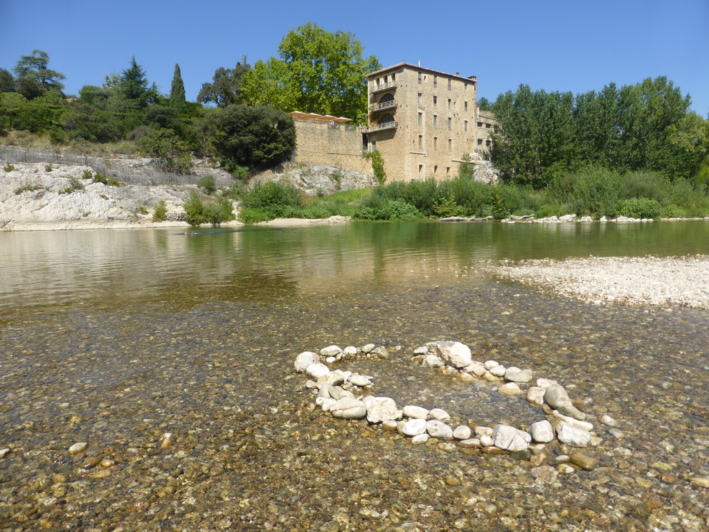 The north side of the Gardon river and a building on the northwest side of the Pont du Gard aqueduct bridge