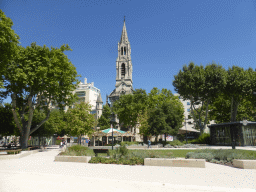 Front of the Eglise Sainte Perpétue church and a carousel at the Esplanade Charles-de-Gaulle square