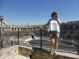 Miaomiao at the upper middle rows of seats, with a view on the east side of the interior of the Arena of Nîmes and the tower of the Eglise Sainte Perpétue church