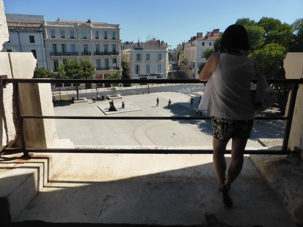 Miaomiao at the upper walkway of the Arena of Nîmes, with a view on the Place des Arènes square with a statue of a bull fighter