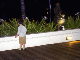 Max with a statue at the Homaya Restaurant of the Inaya Putri Bali hotel, by night