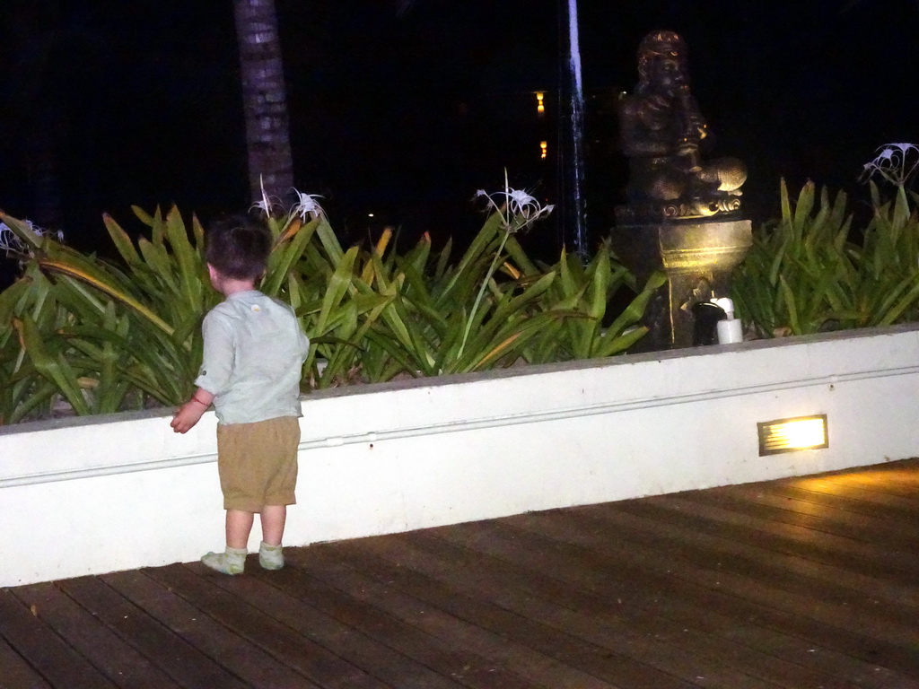 Max with a statue at the Homaya Restaurant of the Inaya Putri Bali hotel, by night