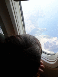 Max looking through the window of the airplane from Rotterdam, with a view on the cliffs on the northwest side of Mallorca