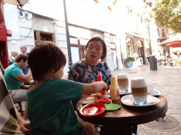 Miaomiao having coffee and Max playing with toys at the terrace of the Hotel Cort Restaurant Café at the Plaça de Cort square