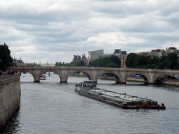 Boat and the Pont Neuf bridge over the Seine river, viewed from the Pont au Change bridge