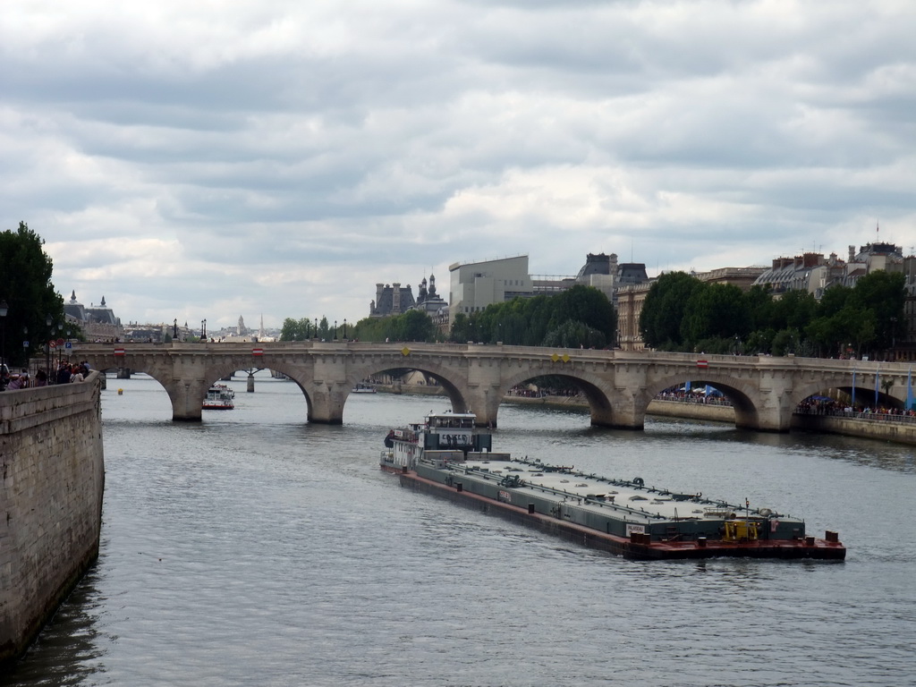 Boat and the Pont Neuf bridge over the Seine river, viewed from the Pont au Change bridge