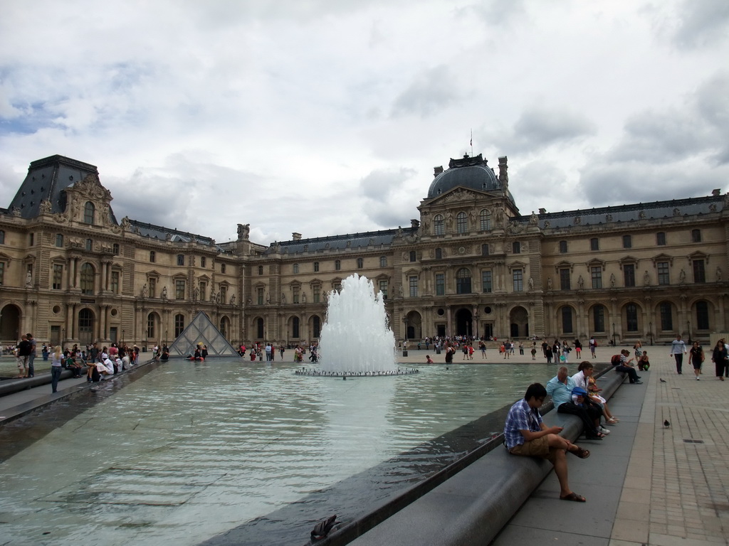 Smaller Louve Pyramid and a fountain at the Cour Napoleon courtyard, and the Louvre Museum
