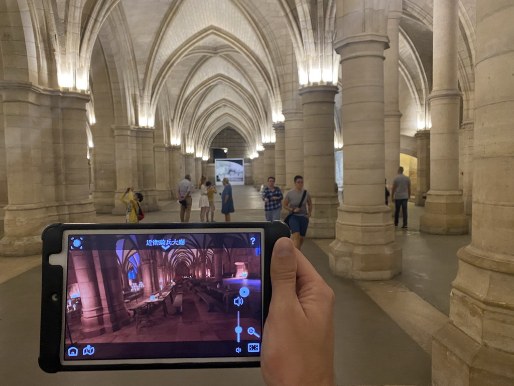 Tim with an iPad showing what the Hall of the Men-at-arms looked like, at the Hall of the Men-at-arms at the Conciergerie building