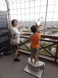 Miaomiao and Max looking through a telescope at the Second Floor of the Eiffel Tower, with a view on the Seine river
