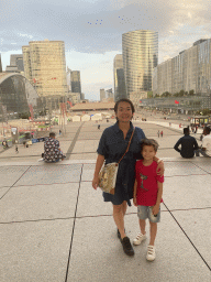 Miaomiao and Max below the Grande Arche de la Défense building, with a view on the CNIT shopping mall, skyscrapers and the Westfield Les 4 Temps shopping mall at the Parvis de la Défense square and the Arc de Triomphe, at sunset