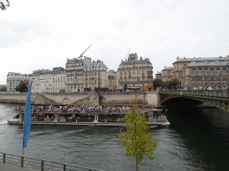 Tour boat and the Pont d`Arcole bridge over the Seine river, viewed from the Quai de l`Hôtel de ville street