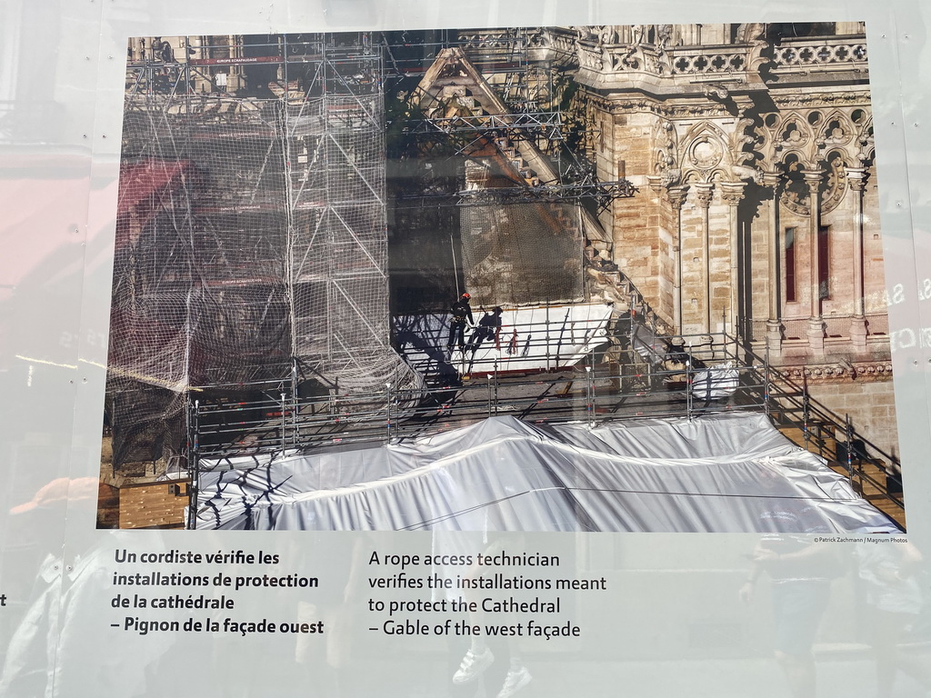 Photograph `A rope access technician verifies the installations meant to protect the Cathedral - Gable of the west facade` at the exhibition `Notre-Dame de Paris - The first months of a renaissance` at the Rue du Cloître-Notre-Dame street, with explanation