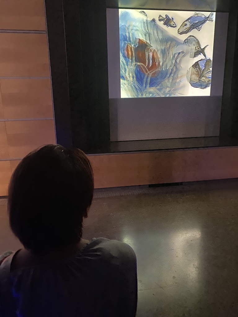 Miaomiao looking at a TV screen at the ground floor of the Grande Galerie de l`Évolution museum