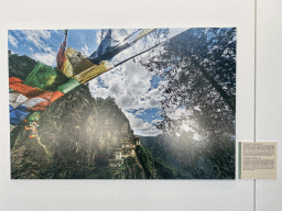 Photograph of Paro Taksang, the `Tiger`s Lair`, at the exhibition `Hymne à la Beauté` at the top floor of the Grande Arche de la Défense building, with explanation