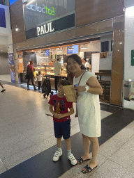 Miaomiao and Max with a croissant in front of the Paul bakery at the La Défense railway station