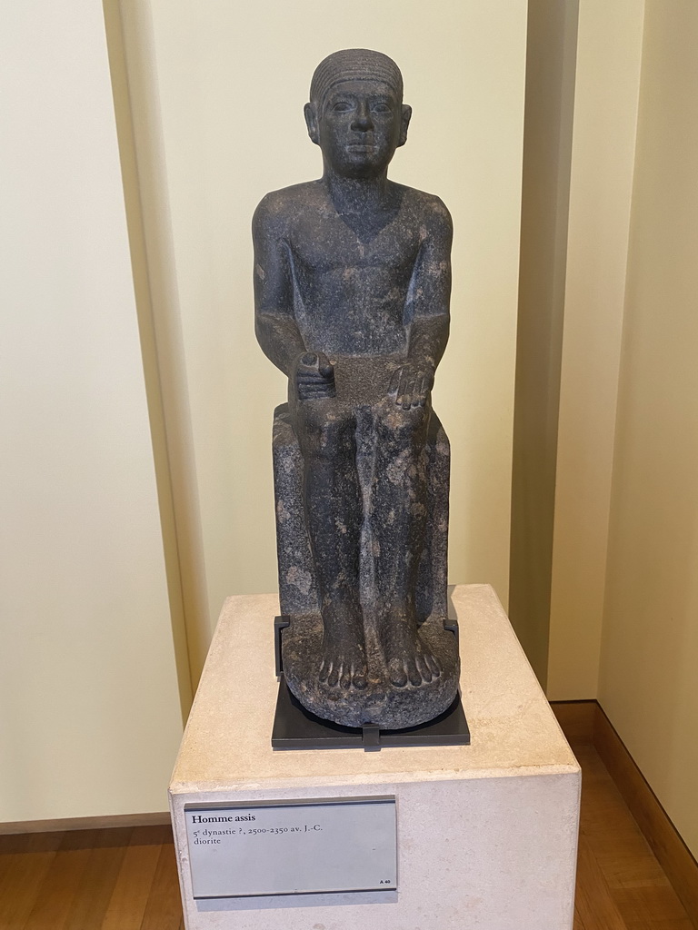 Statue of a sitting man at the First Floor of the Sully Wing of the Louvre Museum, with explanation