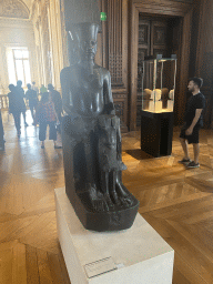 Statue of the God Amon protecting Pharaoh Tutankhamun at the First Floor of the Sully Wing of the Louvre Museum, with explanation