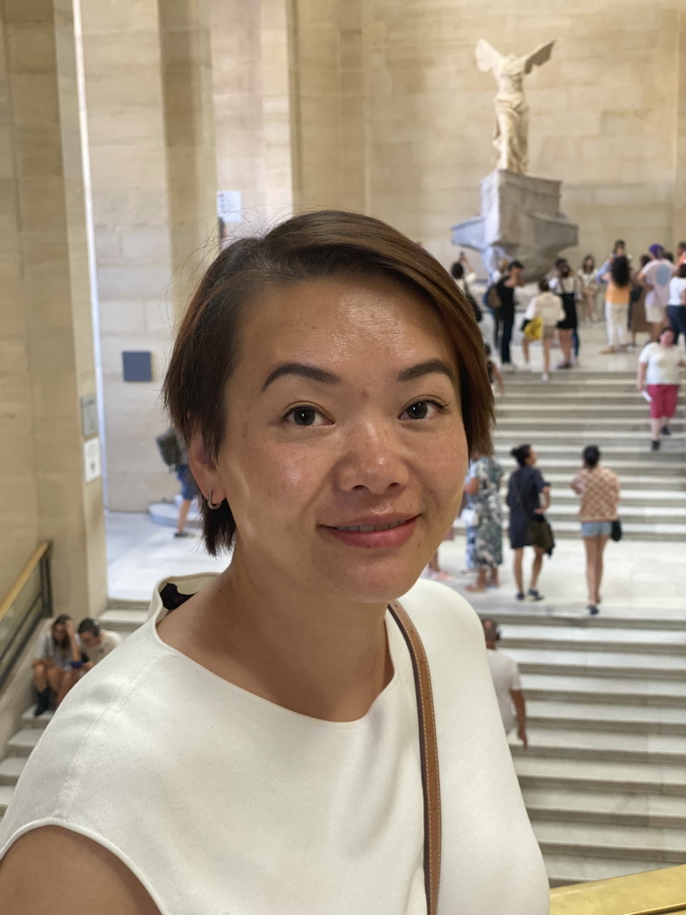 Miaomiao at the First Floor of the Denon Wing of the Louvre Museum, with a view on the statue `Winged Victory of Samothrace` at the Daru Staircase