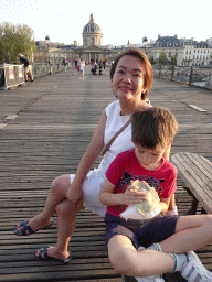 Miaomiao and Max eating a crêpe at the Pont des Arts bridge over the Seine river, with a view on the Institut de France building