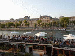The La Balle Au Bond restaurant and a boat on the Seine river and the south side of the Denon Wing of the Louvre Museum, viewed from the Promenade Marceline Loridan-Ivens