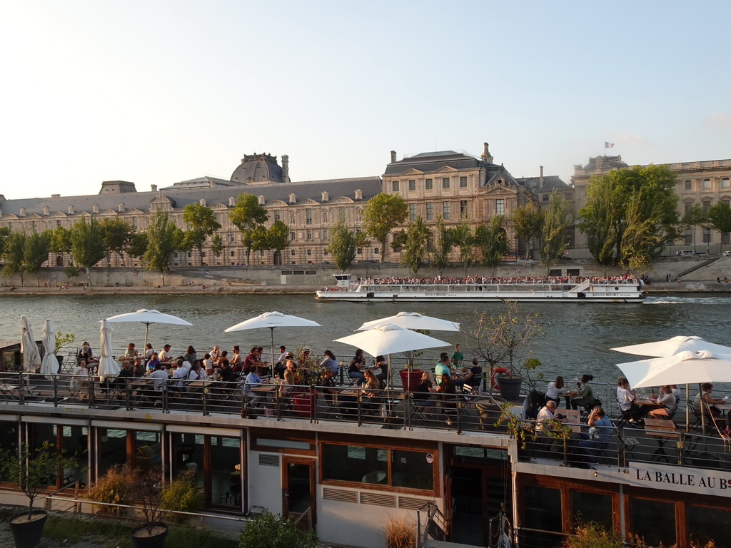 The La Balle Au Bond restaurant and a boat on the Seine river and the south side of the Denon Wing of the Louvre Museum, viewed from the Promenade Marceline Loridan-Ivens