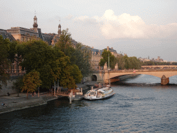 Boat and the Pont du Carrousel bridge over the Seine river and the south side of the Denon Wing of the Louvre Museum, viewed from the Pont Royal bridge