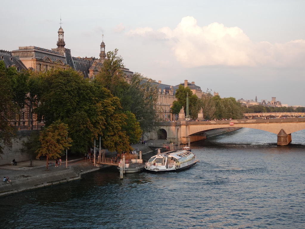 Boat and the Pont du Carrousel bridge over the Seine river and the south side of the Denon Wing of the Louvre Museum, viewed from the Pont Royal bridge