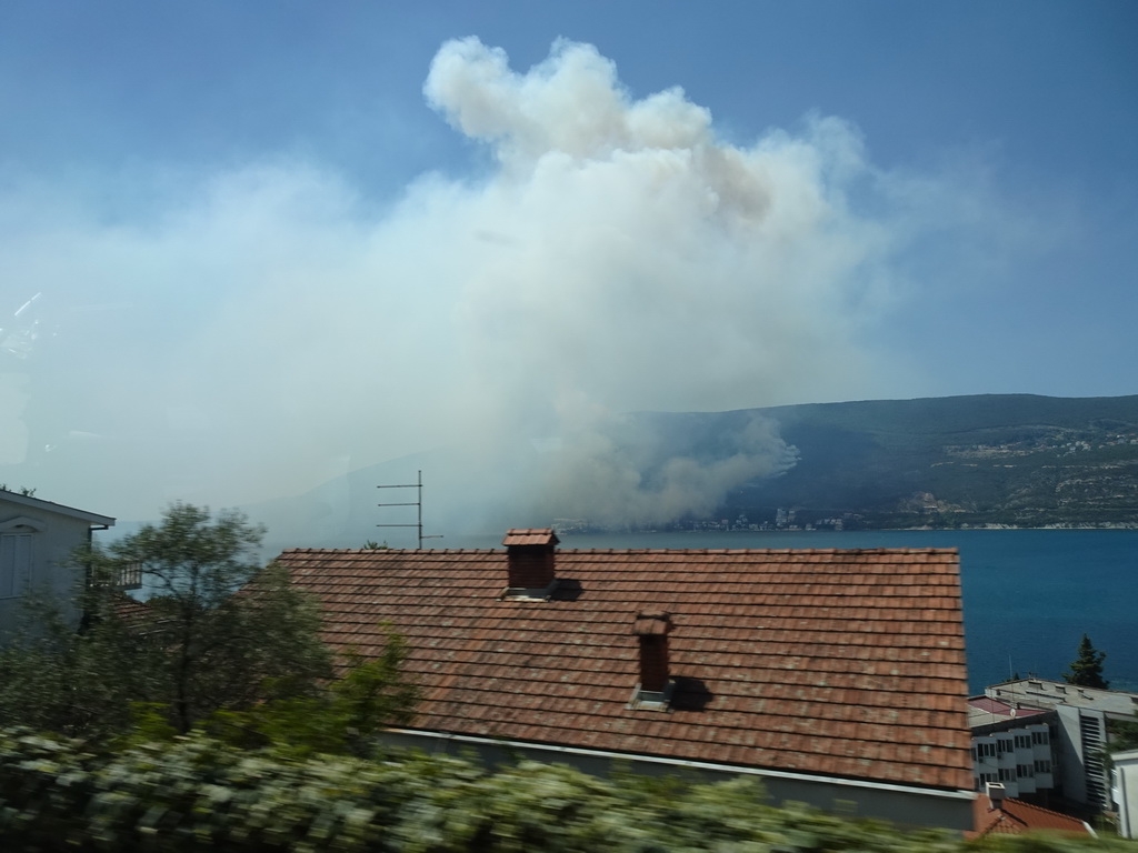 The Bay of Kotor and smoke from a forest fire near the town of Njivice, viewed from the tour bus on the E65 road at the town of Herceg Novi