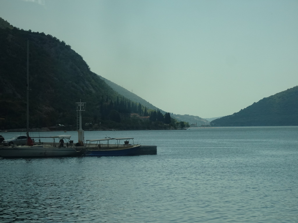 Boats at the Risan Harbour and the Bay of Kotor with the Our Lady of the Rocks Island and the Saint George Island, viewed from the tour bus on the E65 road