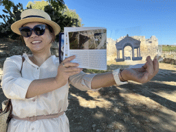 Miaomiao with a reconstruction in a travel guide in front of the south side of the Roman Gate at the south side of the City Walls at the Ancient City of Perge