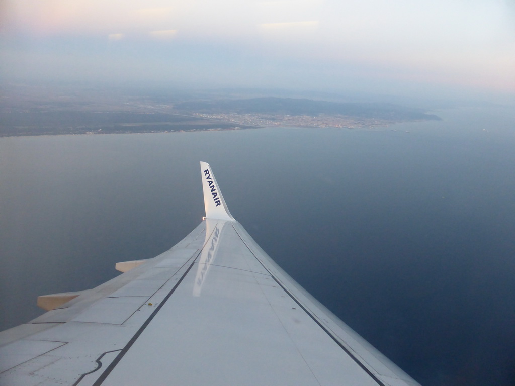 The left wing of our Ryanair airplane, with a view on the city of Livorno