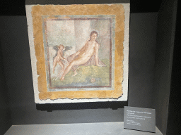 Painting `Narcissus looking at his reflection in the water and a cherub` at the `Art and Sensuality in Pompeii Houses` exhibition at the Palestra Grande building at the Pompeii Archeological Site, with explanation