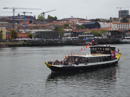 Boat on the Douro river and Vila Nova de Gaia with the Gaia Cable Car building, viewed from the Cais da Estiva street