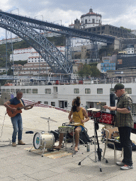 Musicians at the Cais da Ribeira street, with a view on the Ponte Luís I bridge over the Douro river and Vila Nova de Gaia with the Mosteiro da Serra do Pilar monastery