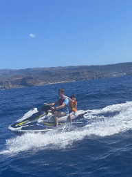 Tim and Max on a jet ski in front of the coastline