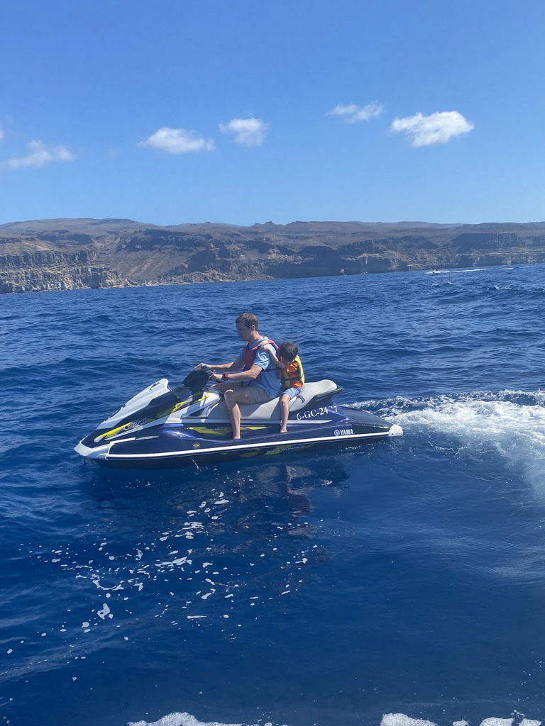 Tim and Max on a jet ski in front of the coastline